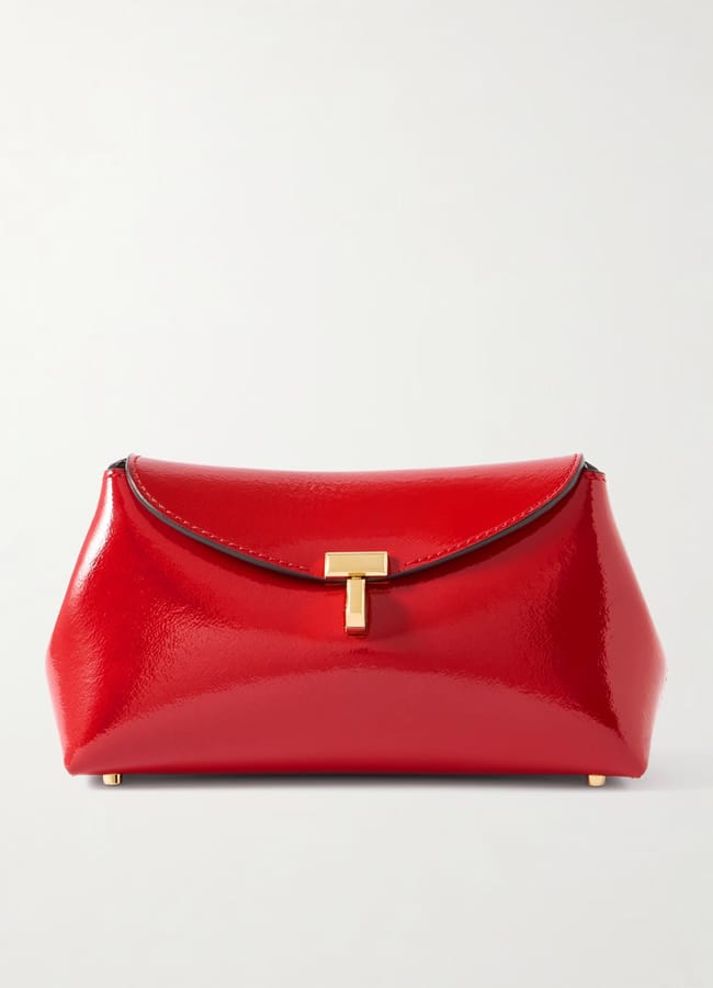 A glossy red leather clutch bag, perfect for lovers of red accessories, features a gold T-shaped clasp and black trim, displayed against a plain white background.