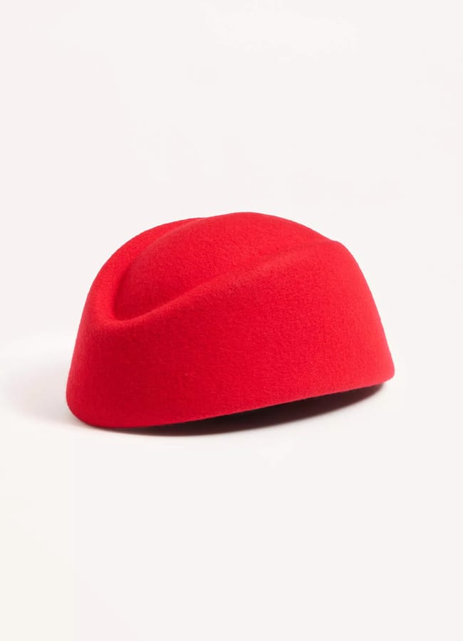 A bright red, wool felt pillbox hat with a smooth, rounded shape—a timeless choice among red accessories—resting on a plain white background.