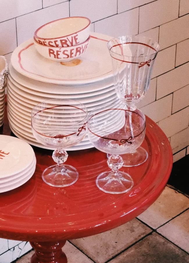A red table, complementing red and pink interiors, holds stacked white plates, a 