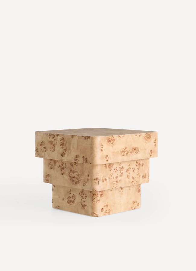 A square, stacked block-style side table made of light-coloured wood with a speckled, natural grain pattern, set against a plain white background.