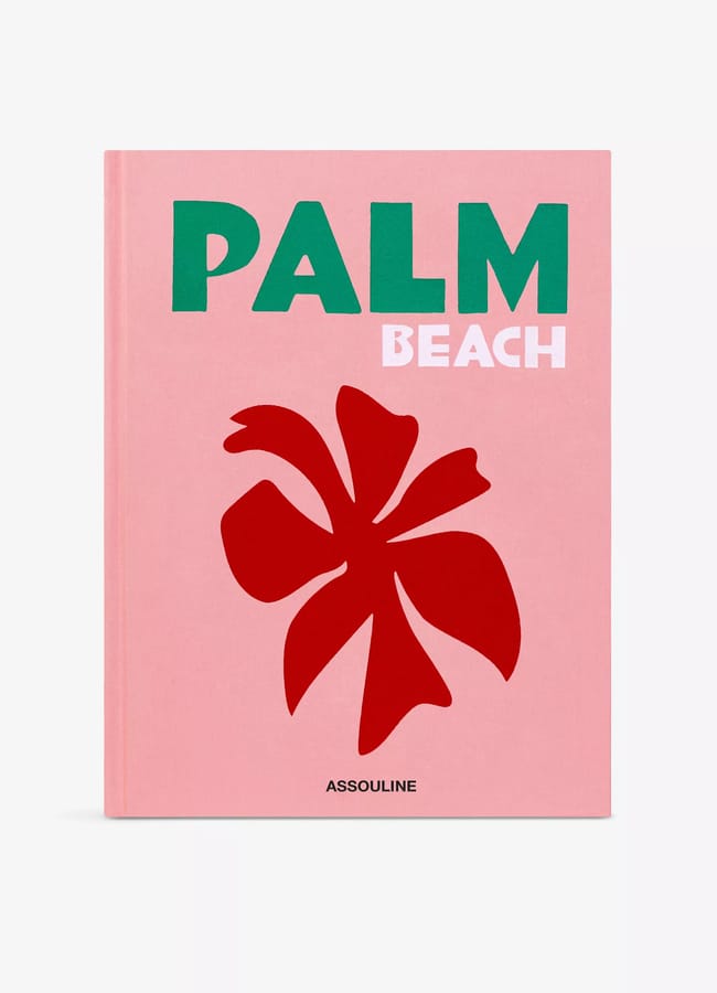 A pink book cover titled PALM BEACH in green and white text, featuring a large red abstract palm leaf illustration reminiscent of red and pink interiors, with the publisher name ASSOULINE at the bottom.