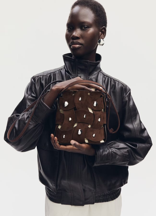 MODEL HOLDING BUCKET BAG IN BROWN SUEDE WITH SILVER EMBELLISHMENT