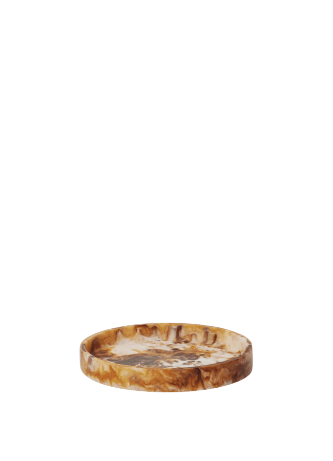 A thin pizza with melted cheese and some browned spots sits on a plain white background, photographed from the side at a low angle—reminiscent of stylish high street homeware photography.