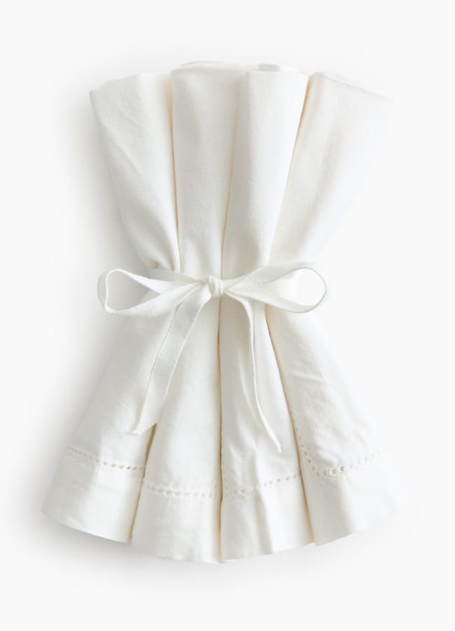 A white serviette tied to a white ribbon, perfect for adding a touch of high street homeware elegance to your table setting.