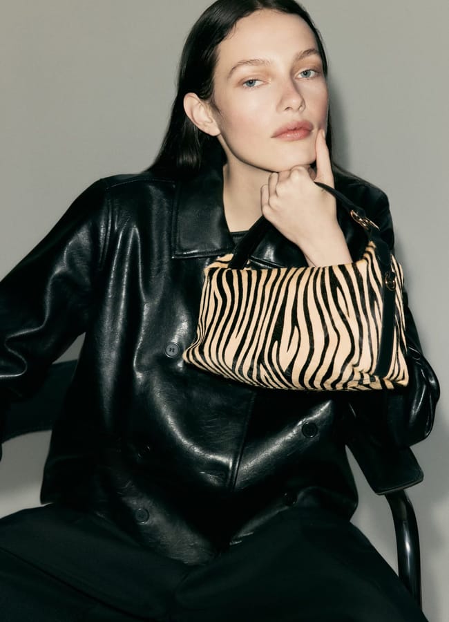 model wearing leather jacket and holding zebra print Leather crossbody bag