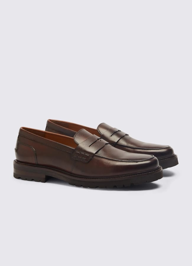 A pair of dark brown leather loafers with a low heel, penny slot detail, and rubber soles—perfect for Casual Date Night Looks—are positioned side by side on a light grey background.