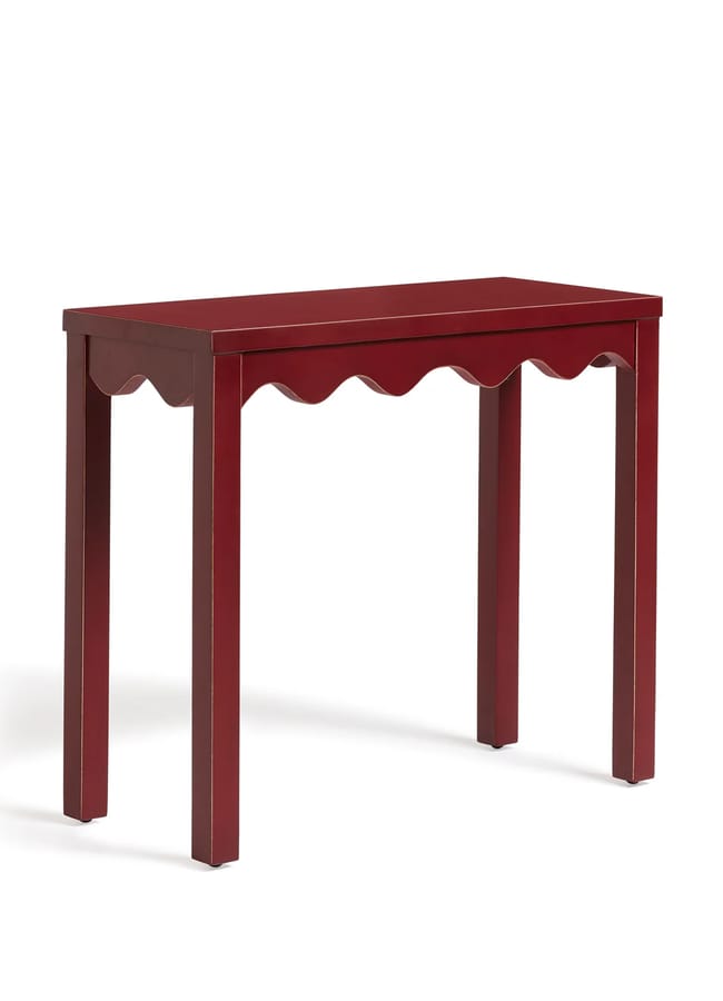 A small red wooden table with four straight legs and a decorative scalloped edge under the tabletop, perfect for adding charm to red and pink interiors, photographed against a plain white background.