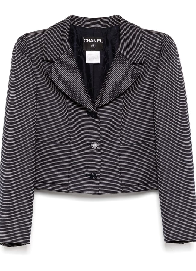 A black and white pinstriped Chanel blazer featuring a wide notched collar, three buttons down the front, and long sleeves—perfect for a modern Wuthering Heights wardrobe. The inside label and quilted lining are visible.