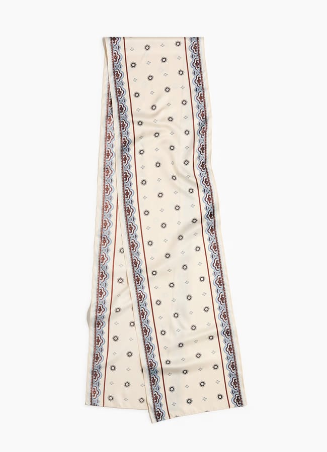 A long, cream-coloured scarf from the H&M new season, featuring small blue and red motifs in the centre and intricate blue and red borders along the edges.