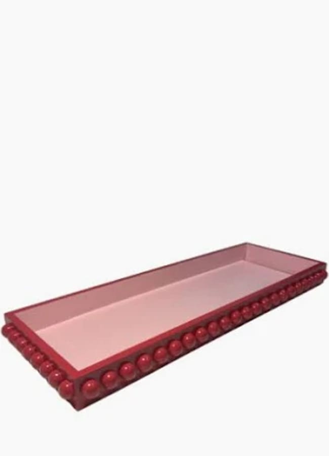 A rectangular pink tray with raised red borders, perfect for red and pink interiors, adorned with a row of round red beads along the edges and set against a plain white background.