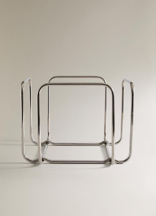 A minimalist chrome metal rack with a geometric design, inspired by high street homeware trends, placed on a neutral background—perfect for holding magazines, vinyl records, or files.