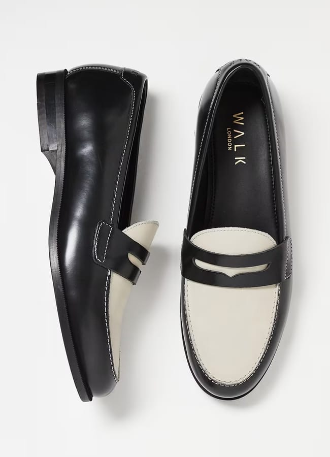 A pair of black and white leather loafers, with WALK LONDON inscribed inside. Shown from a top and side view on a white background, these classic penny loafers are perfect for effortless Casual Date Night Looks.
