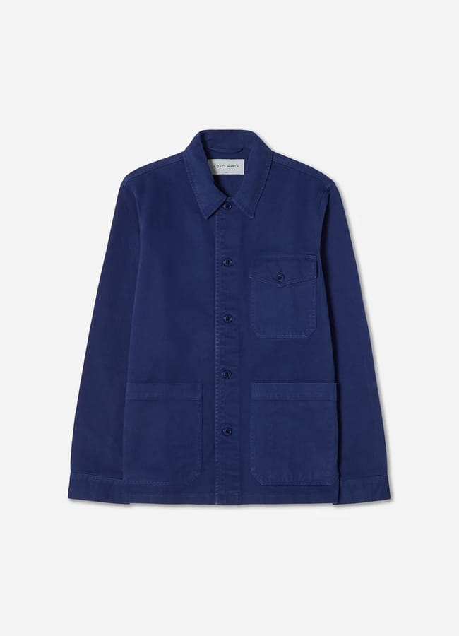 A blue button-up chore jacket with a collar, one chest pocket with a button, and two large front pockets—an essential addition to any collection of men's jackets—laid flat on a white background.