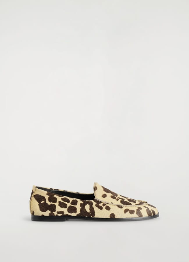 A single flat slip-on shoe with a pointed toe, featuring a tan and dark brown animal print pattern, perfect as spring footwear, displayed on a plain, light background.