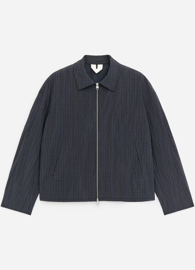 A dark grey pinstriped men's jacket with a front zip, pointed collar, and slanted side pockets, laid flat on a white background.