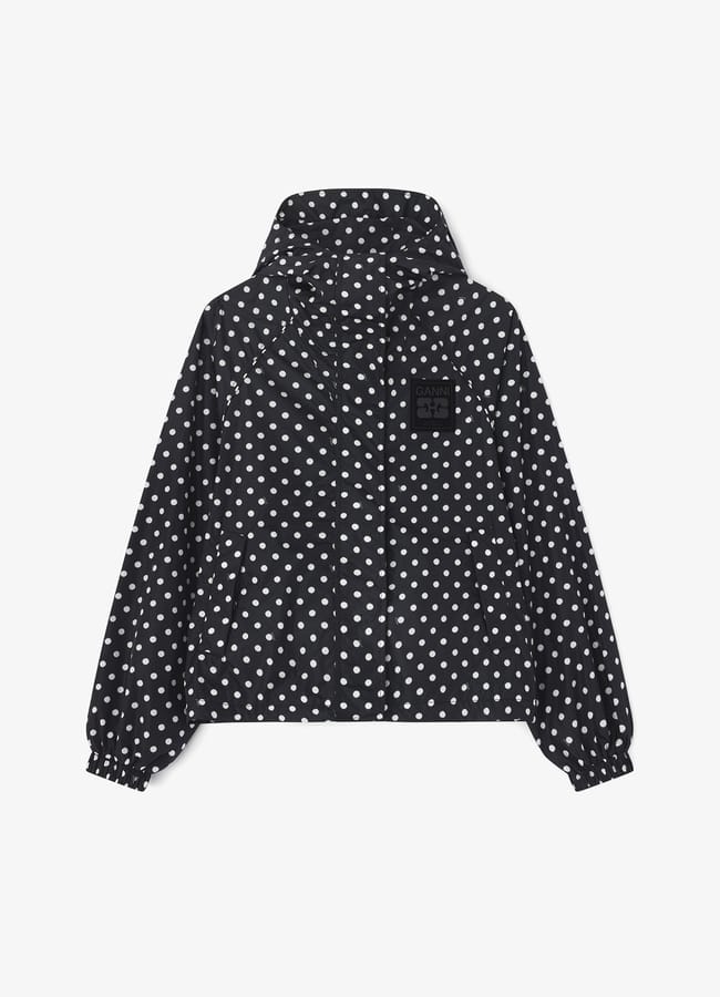 Black hooded jacket with white polka dots, front zip, elasticated cuffs, and a black patch on the left chest—perfect for those seeking stylish waterproof jackets, displayed against a white background.