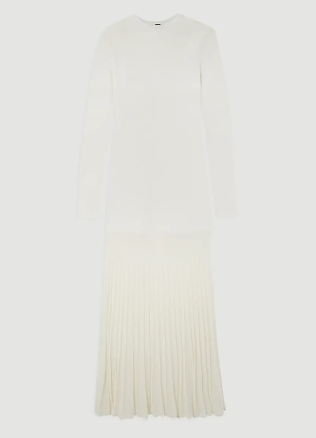 A long-sleeved, ankle-length white dress featuring a sheer fitted top and a pleated skirt section, displayed against a white background.