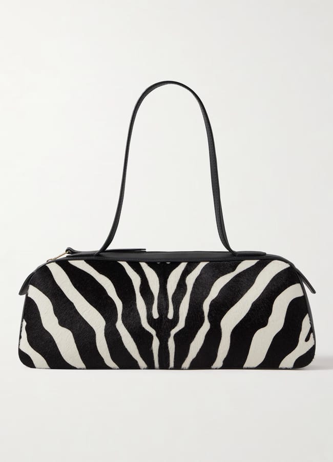 A stylish rectangular handbag with a bold zebra print pattern, featuring a single black strap and a convenient zippered top.