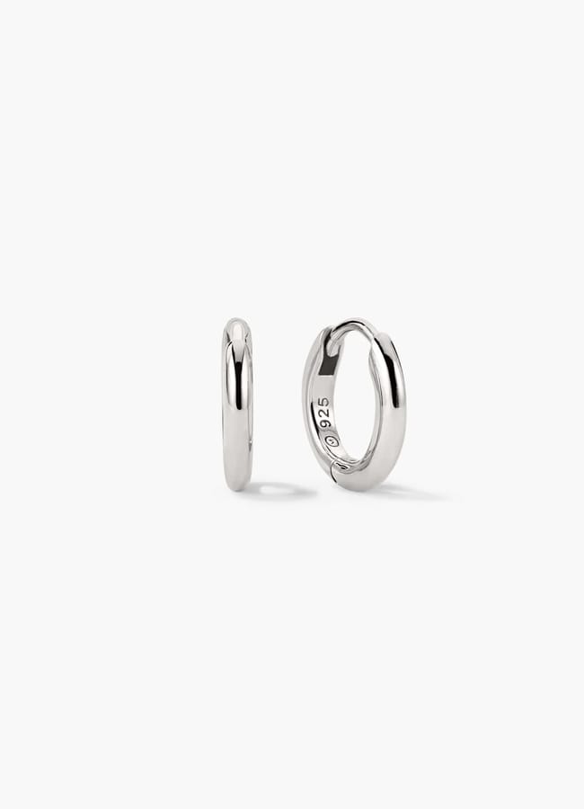 Two small, shiny silver hoop earrings are shown against a plain white background; one earring is facing forward, whilst the other reveals a sheer inner curve with 925 engraved inside.