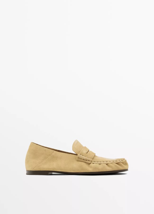 A tan suede loafer, perfect for not freezing on cool days, features a low heel and moccasin-style stitching. These stylish flat shoes are displayed in profile on a plain white background—shop now for ultimate comfort.