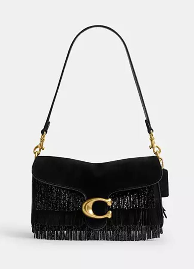 A black handbag with a single shoulder strap, gold fittings, a large gold C clasp, and stylish fringe benefits detailing along the bottom front edge, displayed against a plain white background.