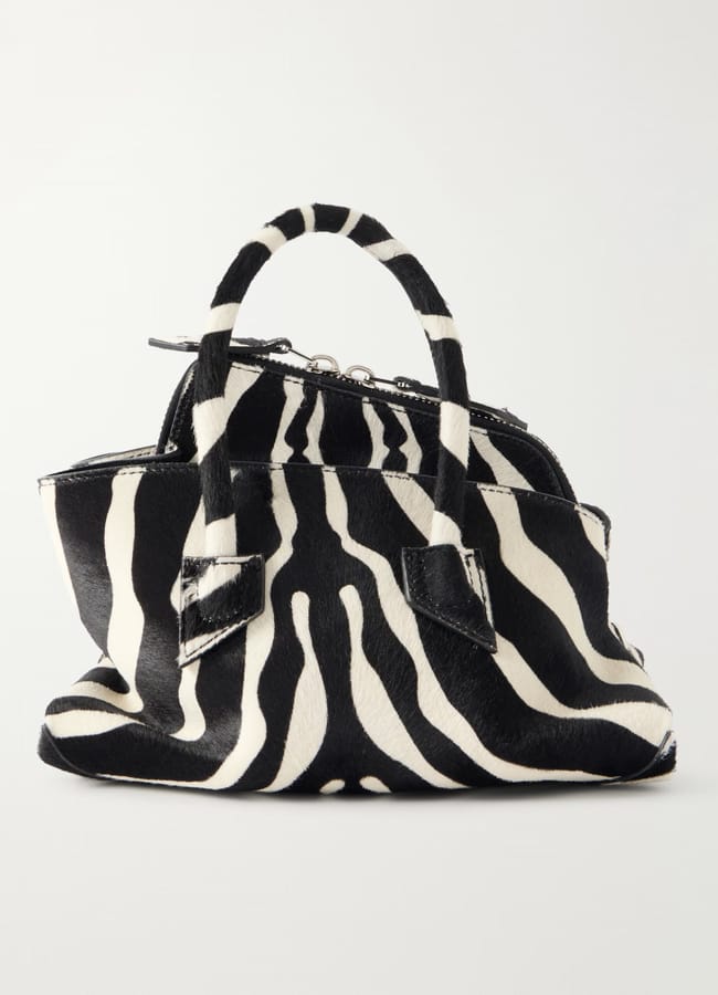 A black and white zebra print handbag featuring two short handles and a zip fastening, shown against a plain white background.