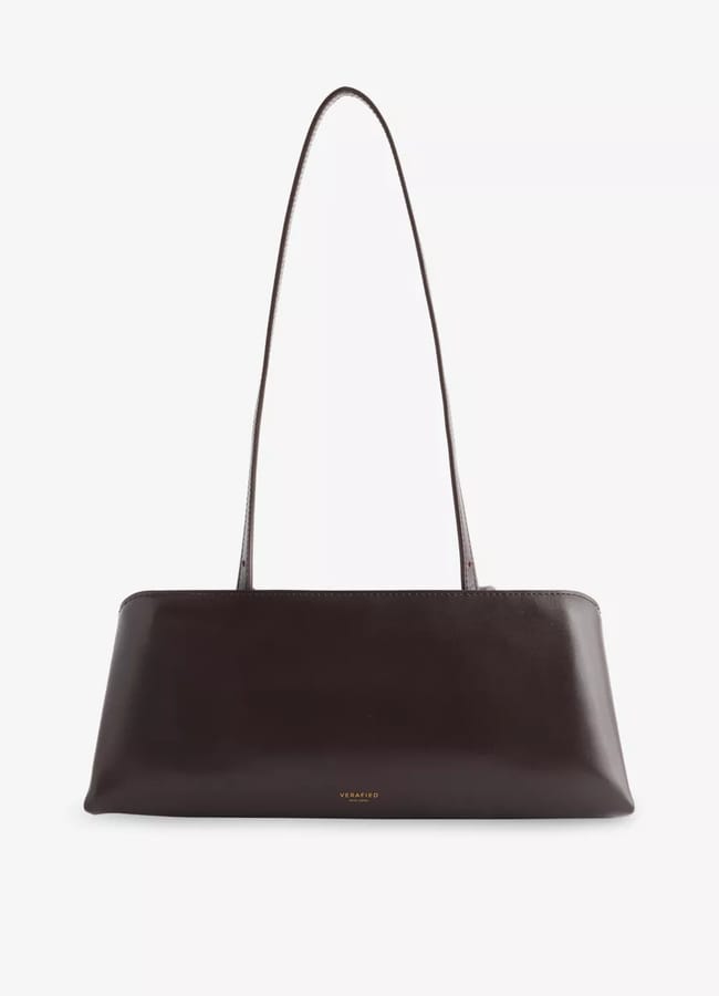 A sleek, rectangular dark brown leather shoulder bag with thin straps and minimal gold text branding on the front—an essential for a cool fashion look inspired by Carolyn Bessette Kennedy—displayed against a plain white background.