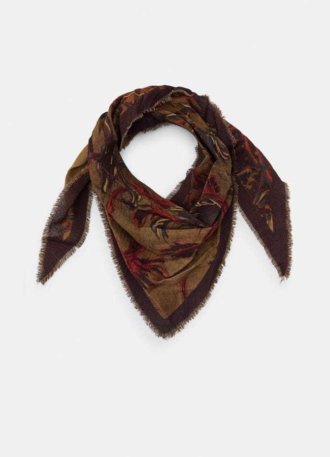 A triangular, fringed scarf with an earthy brown base and a subtle red and green floral pattern, arranged in a loose knot—perfect to recreate outfits or shop my wardrobe for affordable Insta dupes.