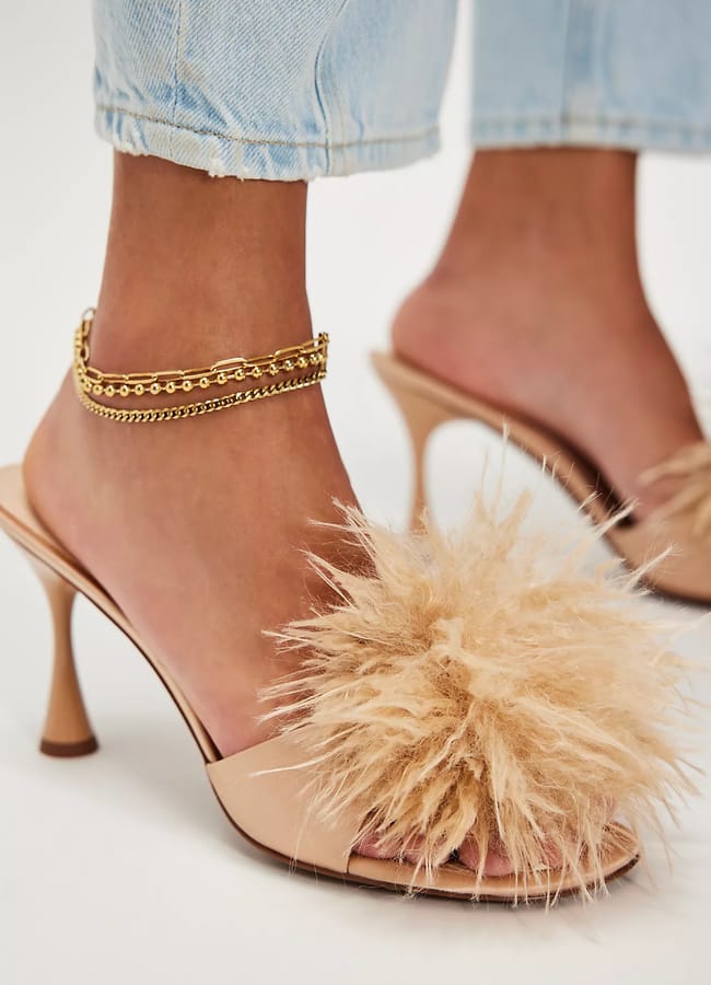 close up of model's feet wearing peach feather topped heels