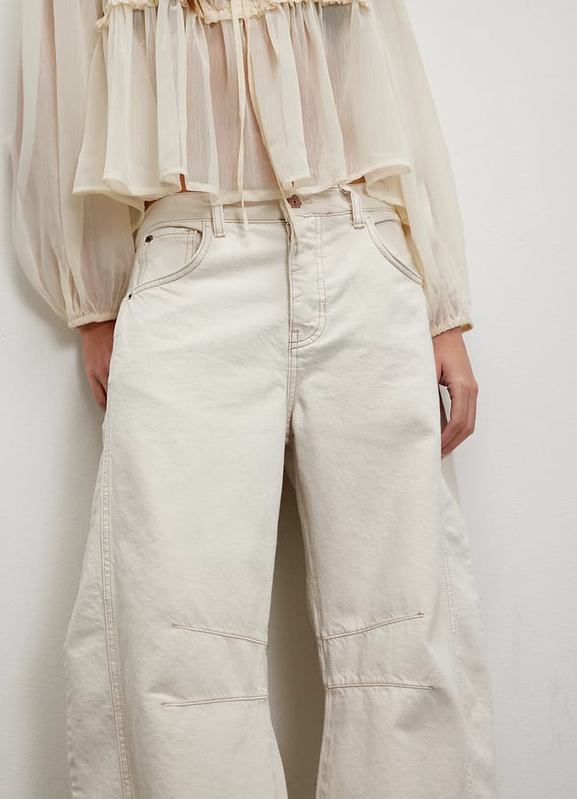 close up of model's lower half wearing fp We The Free Good Luck Mid-Rise Barrel Jeans in white