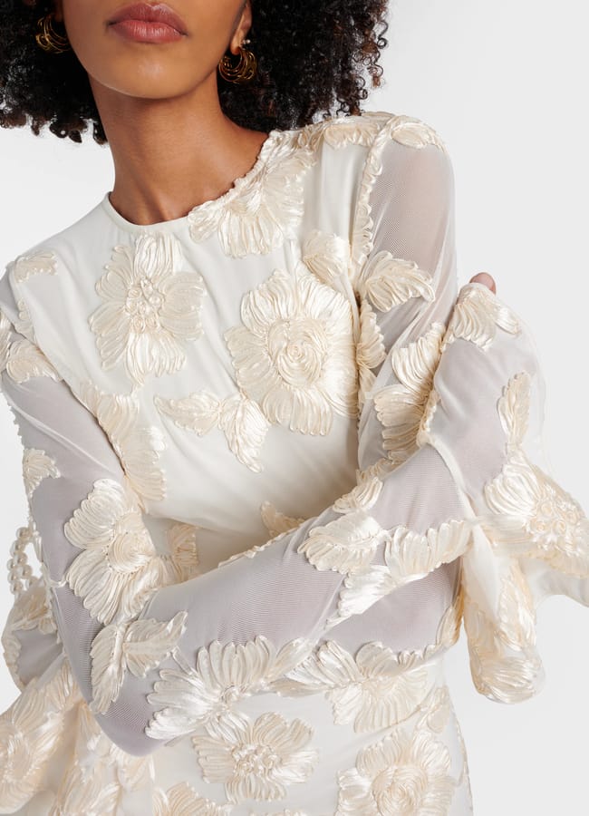 close up of model with arms crossed wearing ivory Rotate Bridal Rosita floral-appliqué mesh minidress