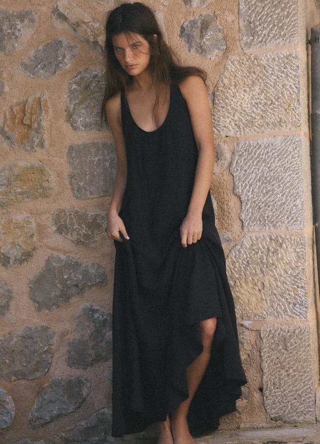 model wearing long black dress by brick wall