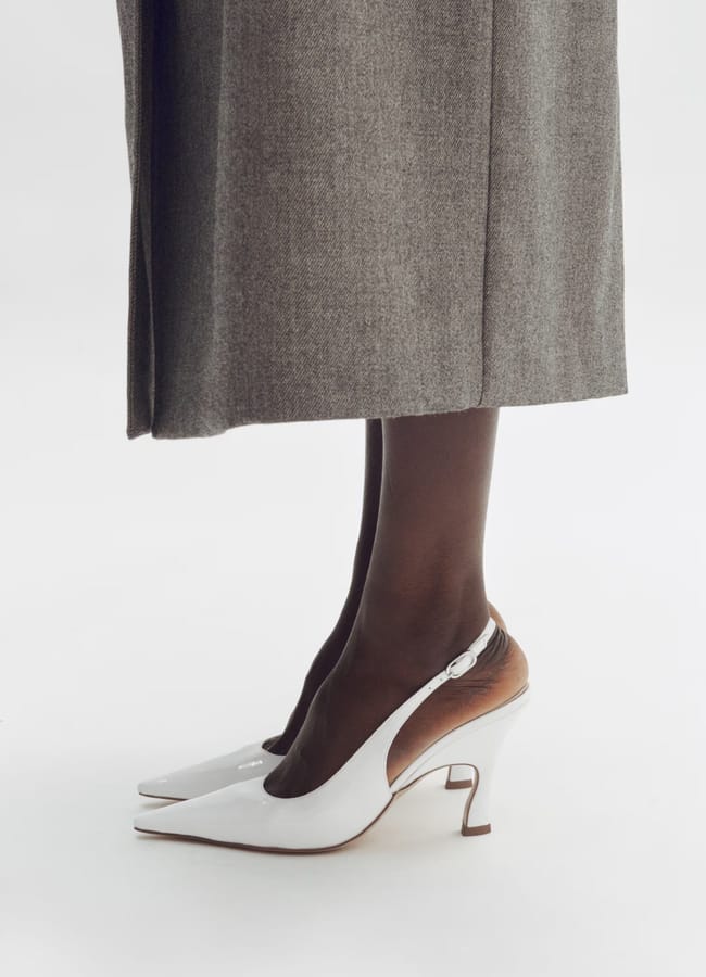 close up of model's feet wearing white point toe slingback heels