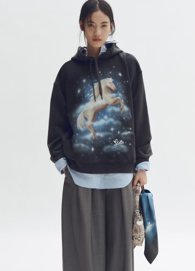 model wearing black hoodie with unicorn motif