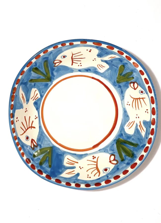 A ceramic plate with a blue border, decorated with painted fish and green leaves around the rim; the centre is plain white with a thin orange circle.