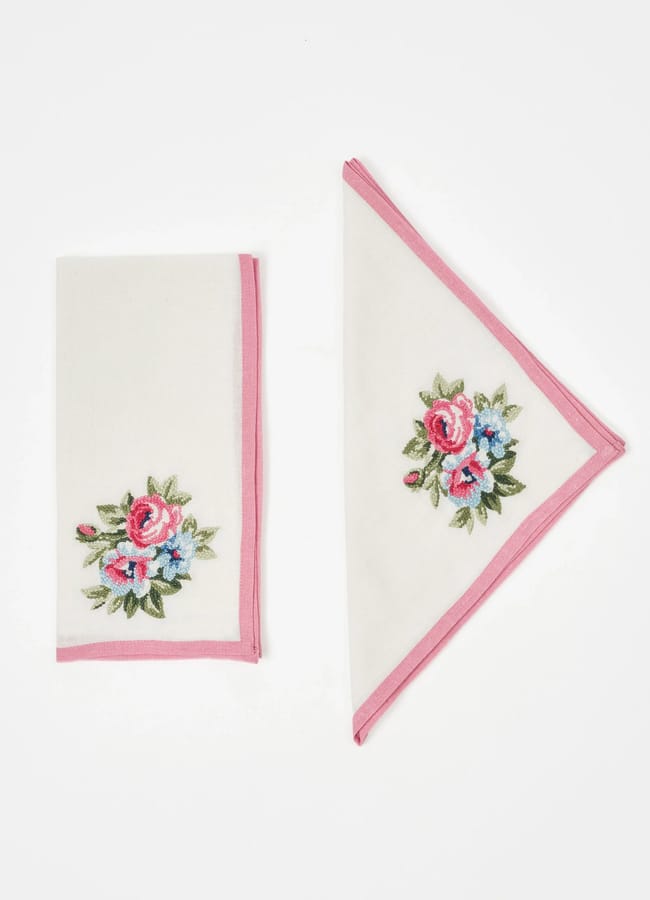 Two white handkerchiefs with pink borders and floral embroidery, one folded into a rectangle and the other into a triangle, displayed on a plain white background.