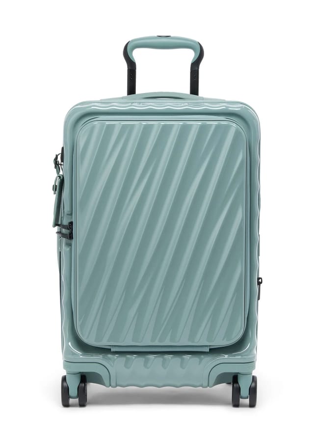A light teal hard-shell suitcase from one of the best suitcase brands features a textured diagonal wave pattern, front zip pocket, four swivel wheels, and a telescopic handle, shown standing upright against a white background.