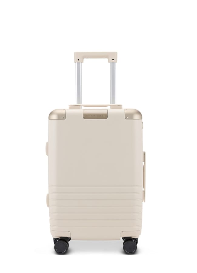 A beige hard-shell suitcase from one of the best suitcase brands, featuring a telescopic handle, four black wheels, and horizontal ridges near the base, stands upright on a white background.