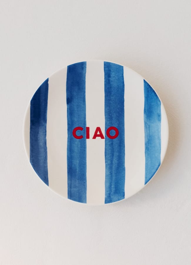 A white plate with bold vertical blue stripes and the word CIAO in red letters in the centre, set against a plain light background.