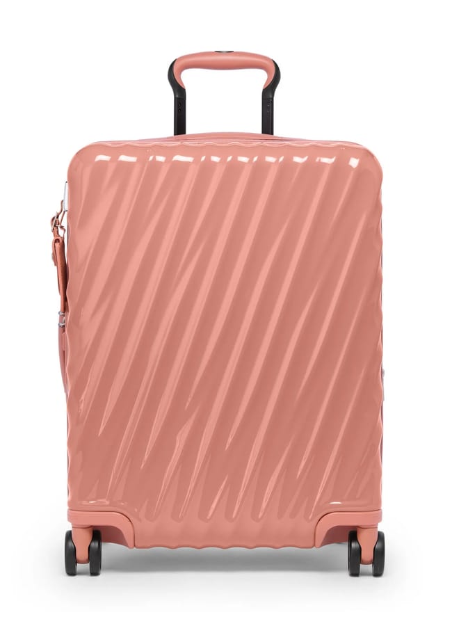 A glossy, rose-pink hard-shell suitcase from one of the best suitcase brands, featuring diagonal ridges, a black telescopic handle, and four black spinner wheels, shown standing upright on a white background.