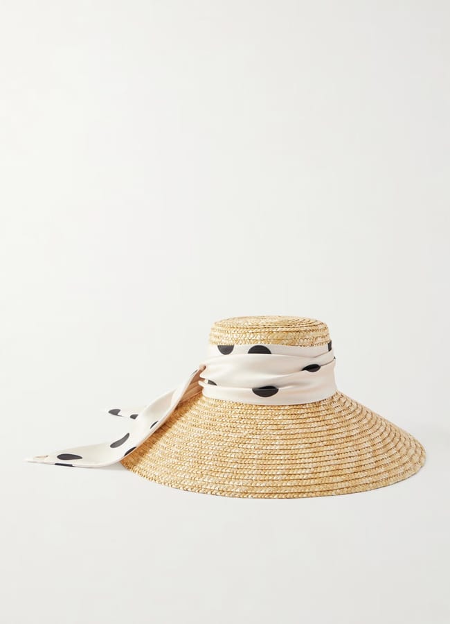 A wide-brimmed straw hat with a cream-coloured scarf featuring large black polka dots tied around the crown, draping down one side—a perfect hot take on banned fascinators for standout summer fashion commentary.