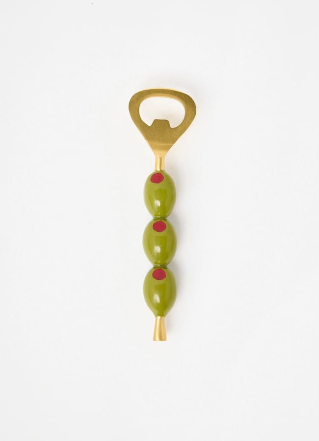 A bottle opener with a gold handle, featuring three green olives stacked vertically on the shaft, each with a red pimento centre—an eye-catching addition to your picnic essentials, all set against a plain white background.