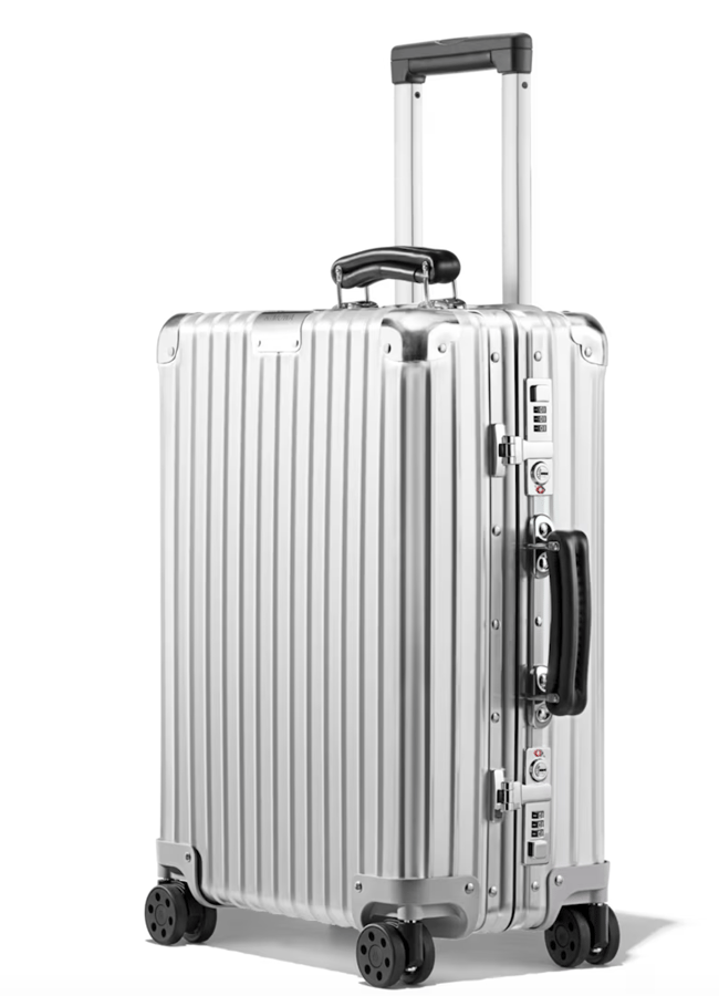 A silver hard-shell suitcase from one of the best suitcase brands, featuring vertical grooves, four wheels, a black side handle, and a telescopic top handle, is positioned on a white background.