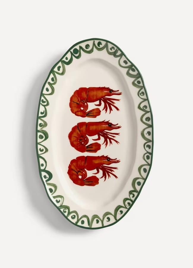 Oval ceramic plate with a green decorative border, perfect for salad season, featuring three painted red prawns arranged side by side in the centre on a white background.
