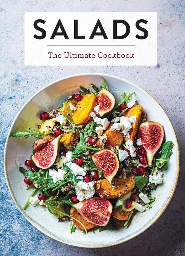 A cookbook cover titled Salads: The Ultimate Cookbook, perfect for salad season, featuring a bowl of rocket, roasted squash, fresh figs, pomegranate seeds, and crumbled cheese on a light, textured surface.