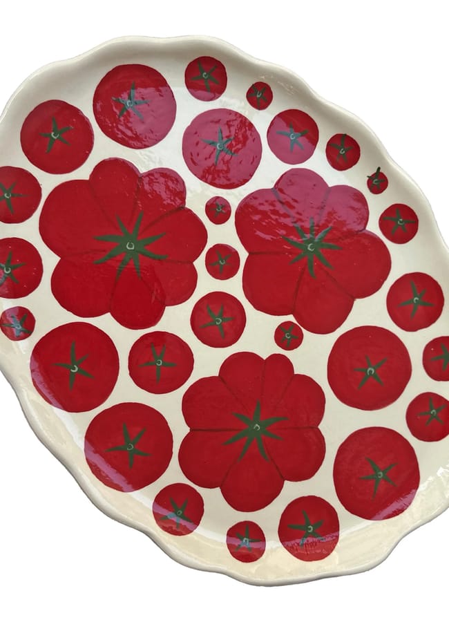 Wavy-edged ceramic plate decorated with various sizes of red tomato slices, each with green centres, on a white background—a perfect addition to your collection of foodie homewares or as a thoughtful culinary gift for kitchen accessories enthusiasts.
