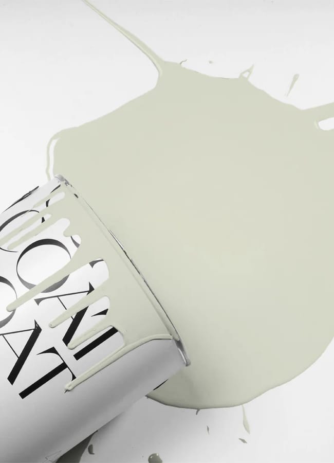 A silver paint tin lies on its side, spilling pale green paint across a white surface, evoking the bold colour palettes often found in maximalist hotels.