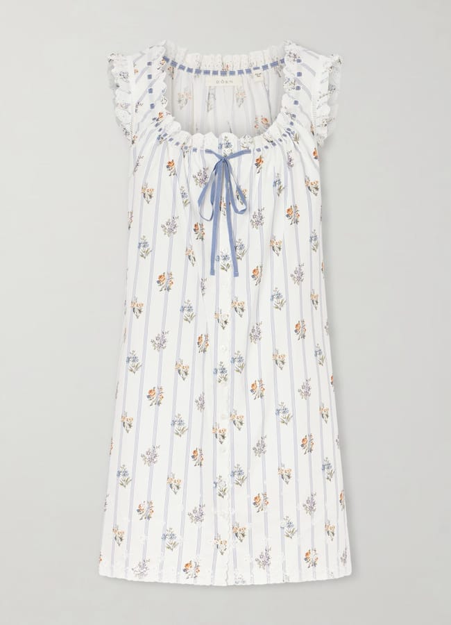 White short-sleeve nightdress with small floral prints, vertical blue stripes, frilled sleeves, and a blue ribbon tie at the neckline—perfect for those seeking inspiration on what to wear in Ibiza for a relaxed and stylish night in. Laid flat on a light background.