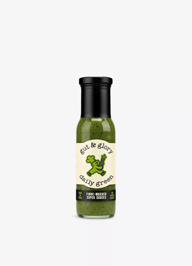 A bottle of Gut & Glory Daily Green fibre-maxxed super sauce, perfect for salad season, featuring a green sauce inside and a label with a cartoon broccoli holding a fork. The bottle has a black cap and white background.