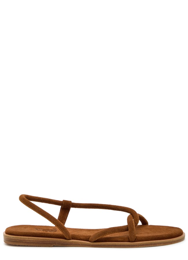 Brown suede flat sandal with thin, criss-crossing straps and an open toe design. The sandal has a simple, minimalist style and a flat sole—perfect for those wondering what to wear in Ibiza, pairing effortlessly with breezy summer outfits.